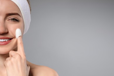 Woman using silkworm cocoon in skin care routine on grey background, closeup. Space for text