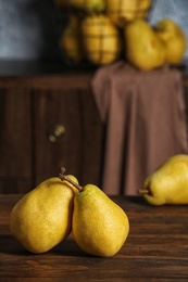 Photo of Fresh ripe pears on wooden table against blurred background