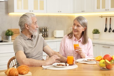 Happy senior couple having breakfast at home