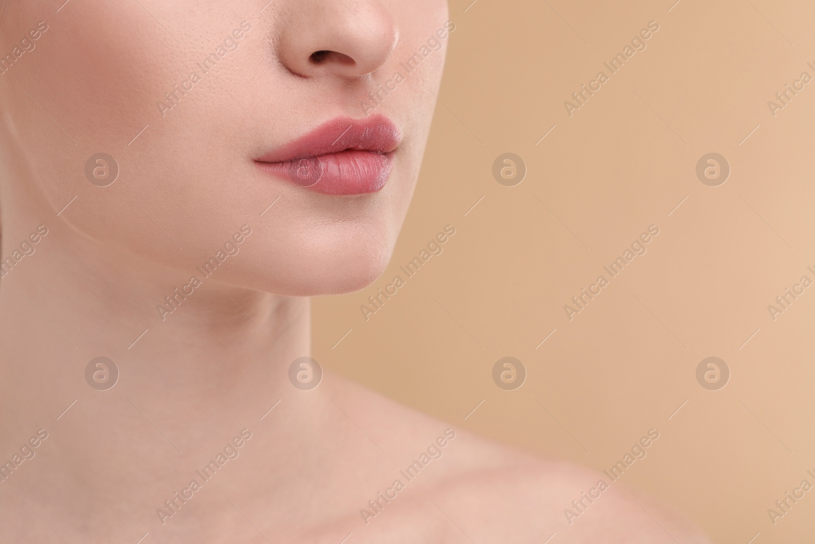 Photo of Young woman with beautiful full lips on beige background, closeup