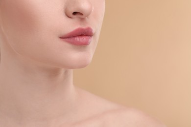 Photo of Young woman with beautiful full lips on beige background, closeup