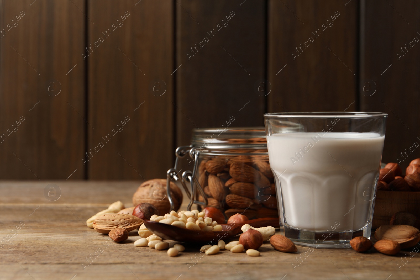 Photo of Vegan milk and different nuts on wooden table. Space for text