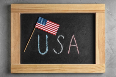 Photo of Flag and phrase USA written on chalkboard, flat lay