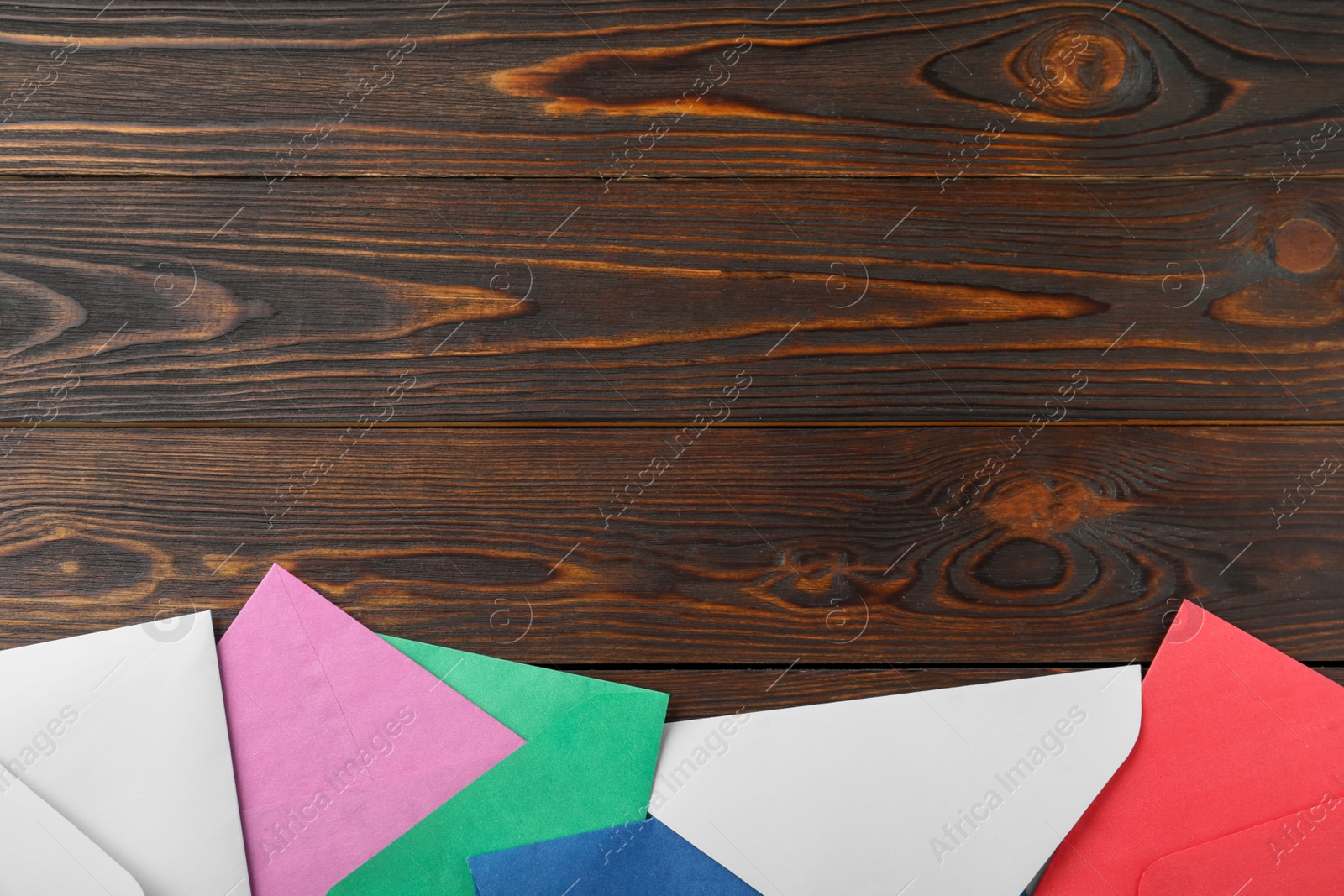 Photo of Colorful paper envelopes on wooden background, flat lay. Space for text