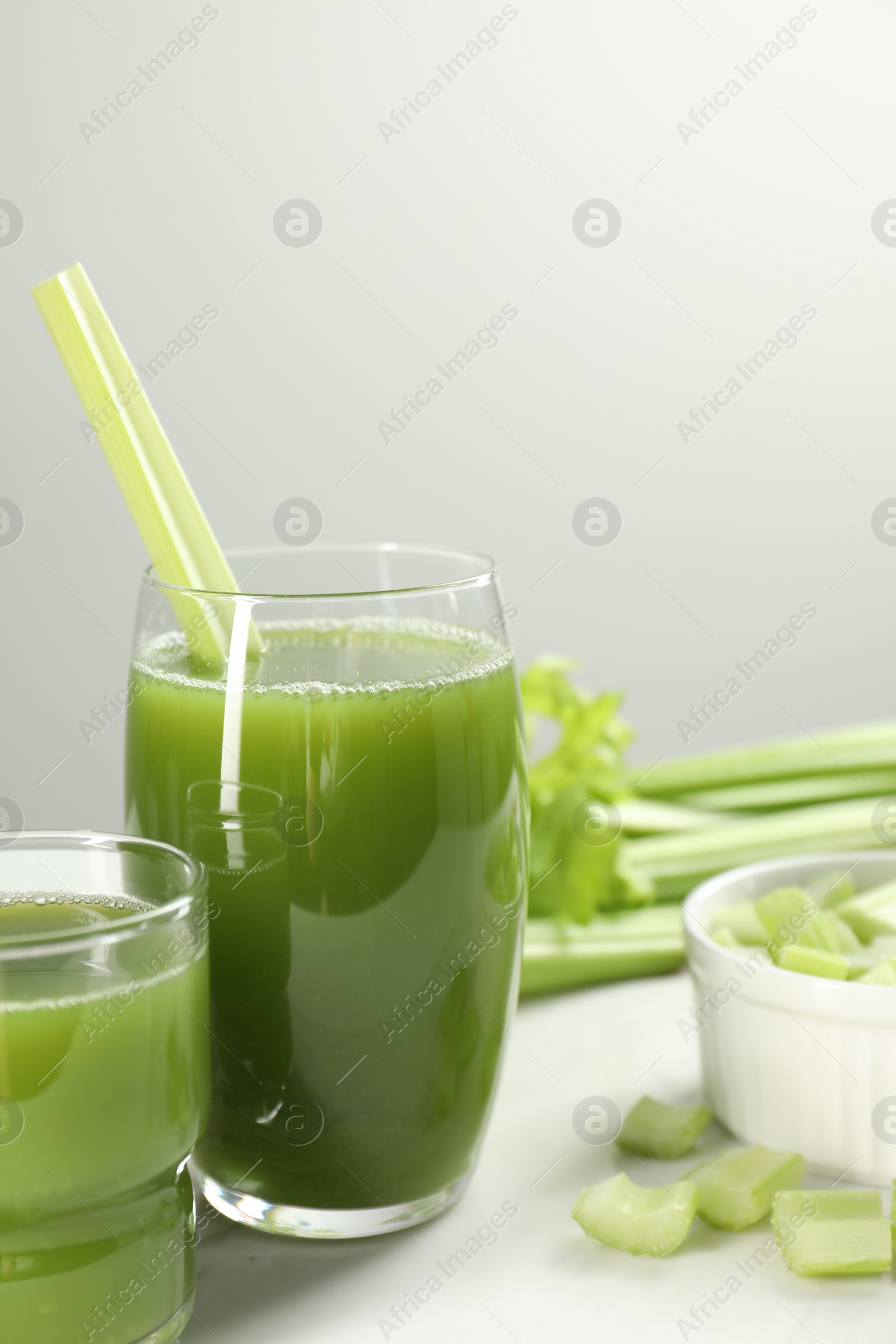 Photo of Glass of delicious celery juice and vegetables on white table