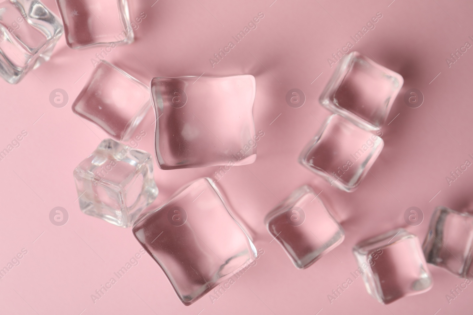 Photo of Crystal clear ice cubes on pink background, flat lay