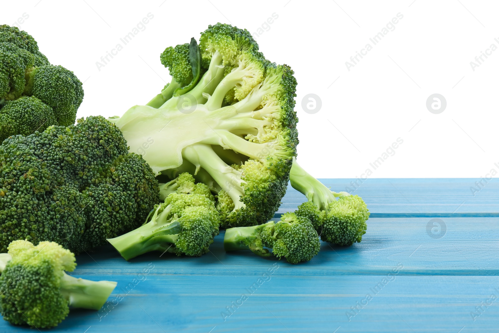 Photo of Fresh broccoli on light blue wooden table against white background. Space for text