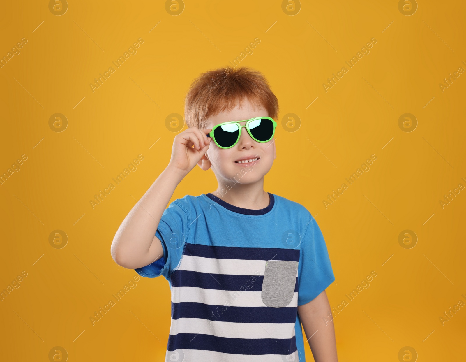 Photo of Cute little boy with sunglasses on yellow background