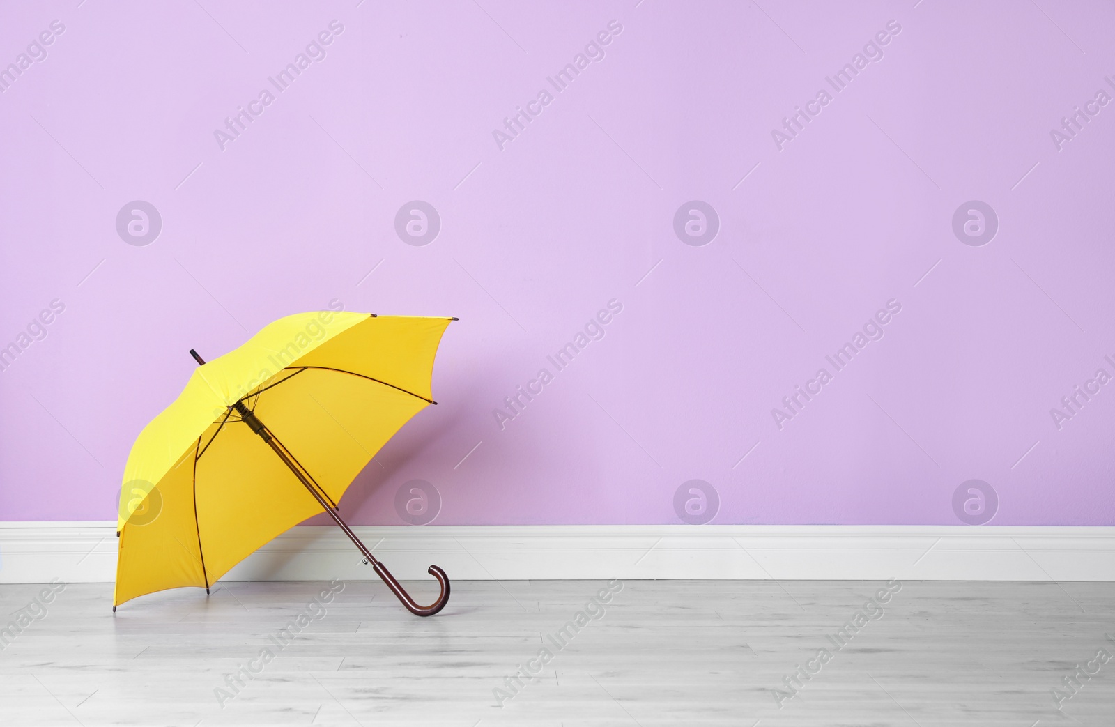 Photo of Beautiful open umbrella on floor near color wall with space for design