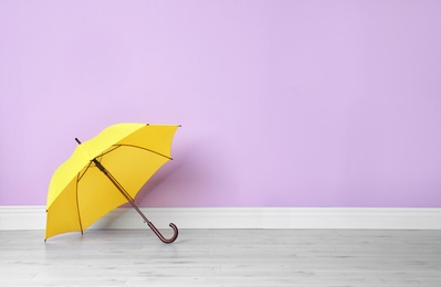 Photo of Beautiful open umbrella on floor near color wall with space for design