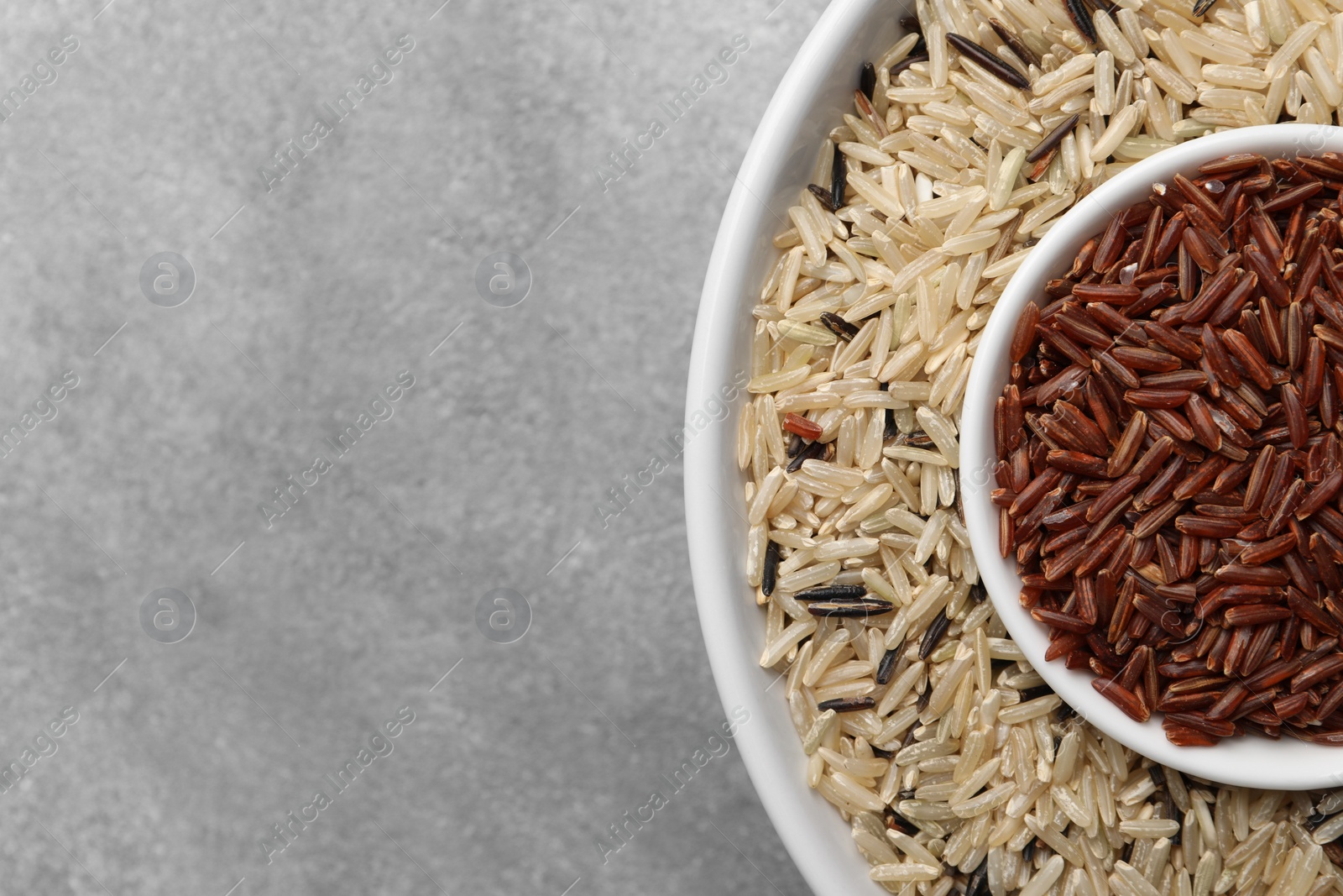 Photo of Different sorts of rice on grey table, top view. Space for text