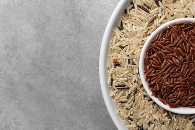 Different sorts of rice on grey table, top view. Space for text