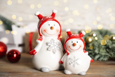 Photo of Funny little snowmen on wooden table. Christmas decor