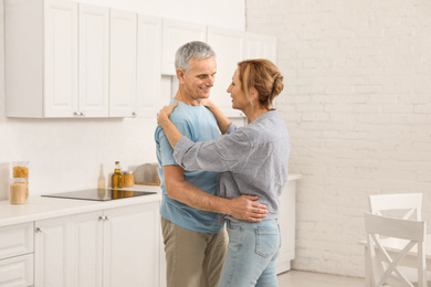 Photo of Happy senior couple dancing together in kitchen