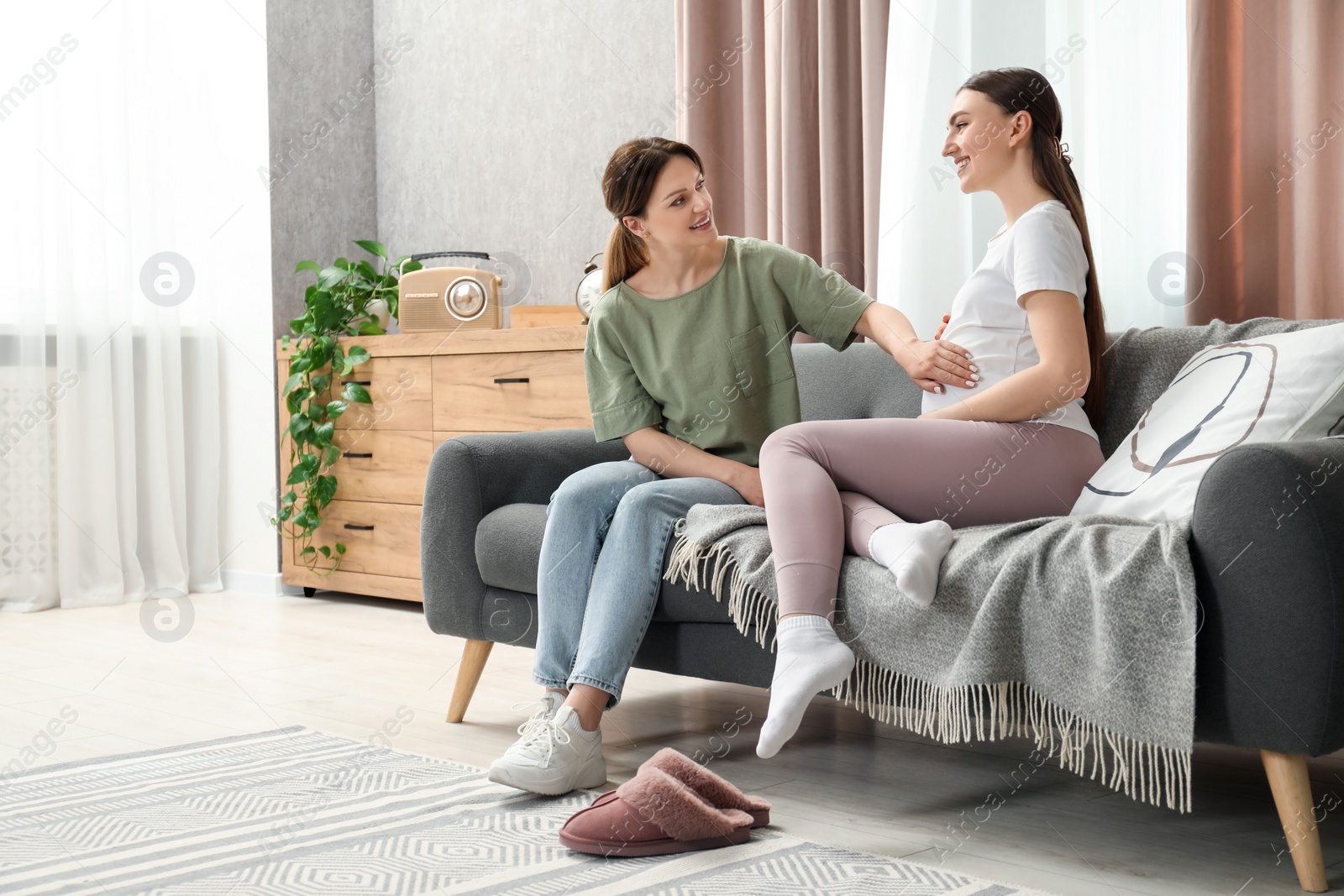 Photo of Doula taking care of pregnant woman on sofa at home. Preparation for child birth