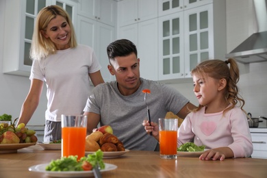 Happy family having breakfast together at table in modern kitchen