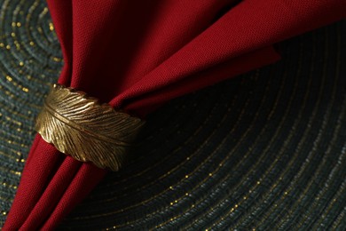 Photo of Red fabric napkin and decorative ring on serving mat, closeup