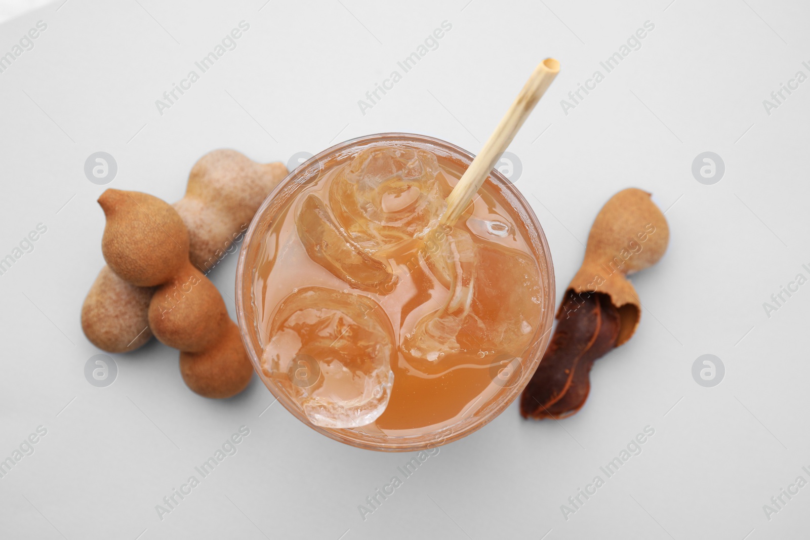 Photo of Tamarind juice and fresh fruits on white background, flat lay