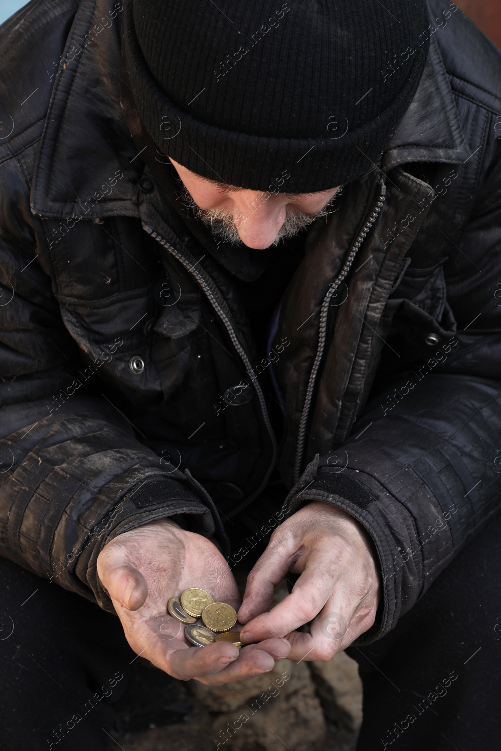 Photo of Poor homeless senior man holding coins outdoors