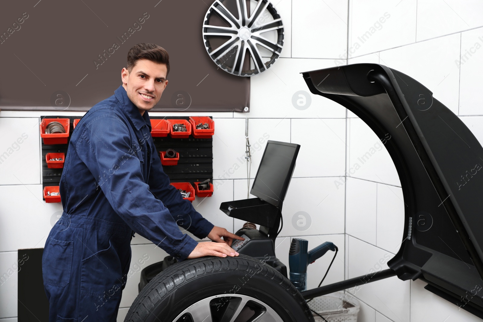 Photo of Man working with wheel balancing machine at tire service