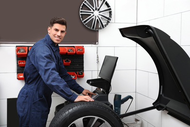 Man working with wheel balancing machine at tire service