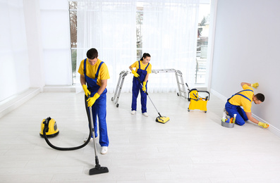 Photo of Team of professional janitors cleaning room after renovation