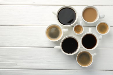 Photo of Different coffee drinks in cups on white wooden table, flat lay. Space for text