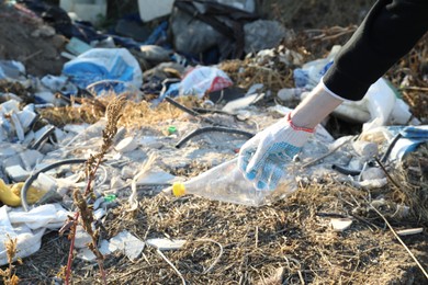 Photo of Woman picking up plastic garbage outdoors, closeup