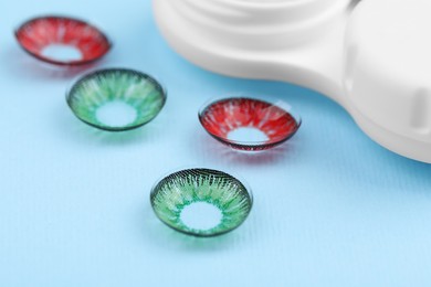 Photo of Different color contact lenses on light blue background, closeup