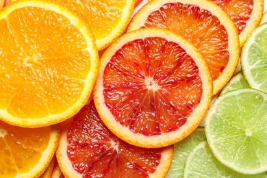 Photo of Slices of fresh citrus fruits as background, top view