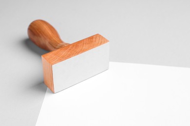 One wooden stamp tool and sheet of paper on light grey background, closeup. Space for text