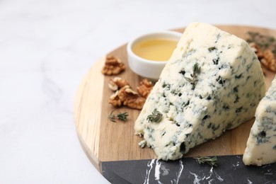 Tasty blue cheese with thyme, honey and walnuts on white marble table, closeup. Space for text