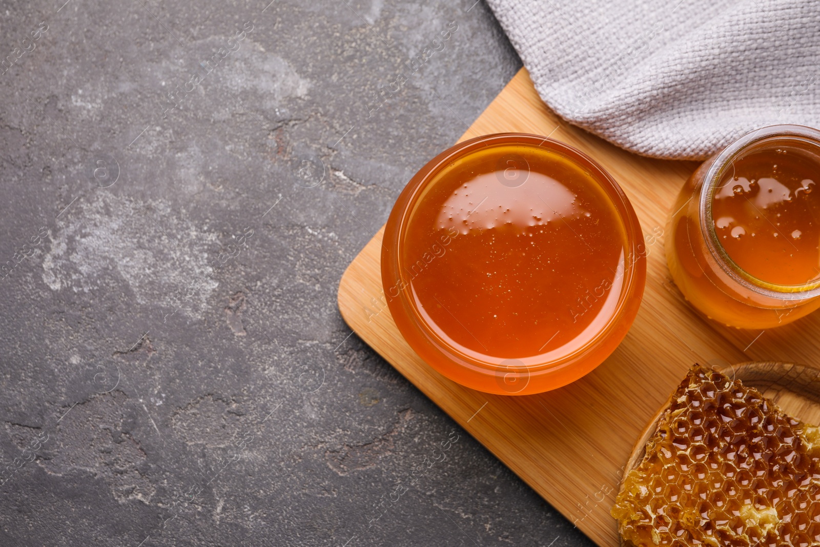 Photo of Tasty aromatic honey on grey table, flat lay. Space for text