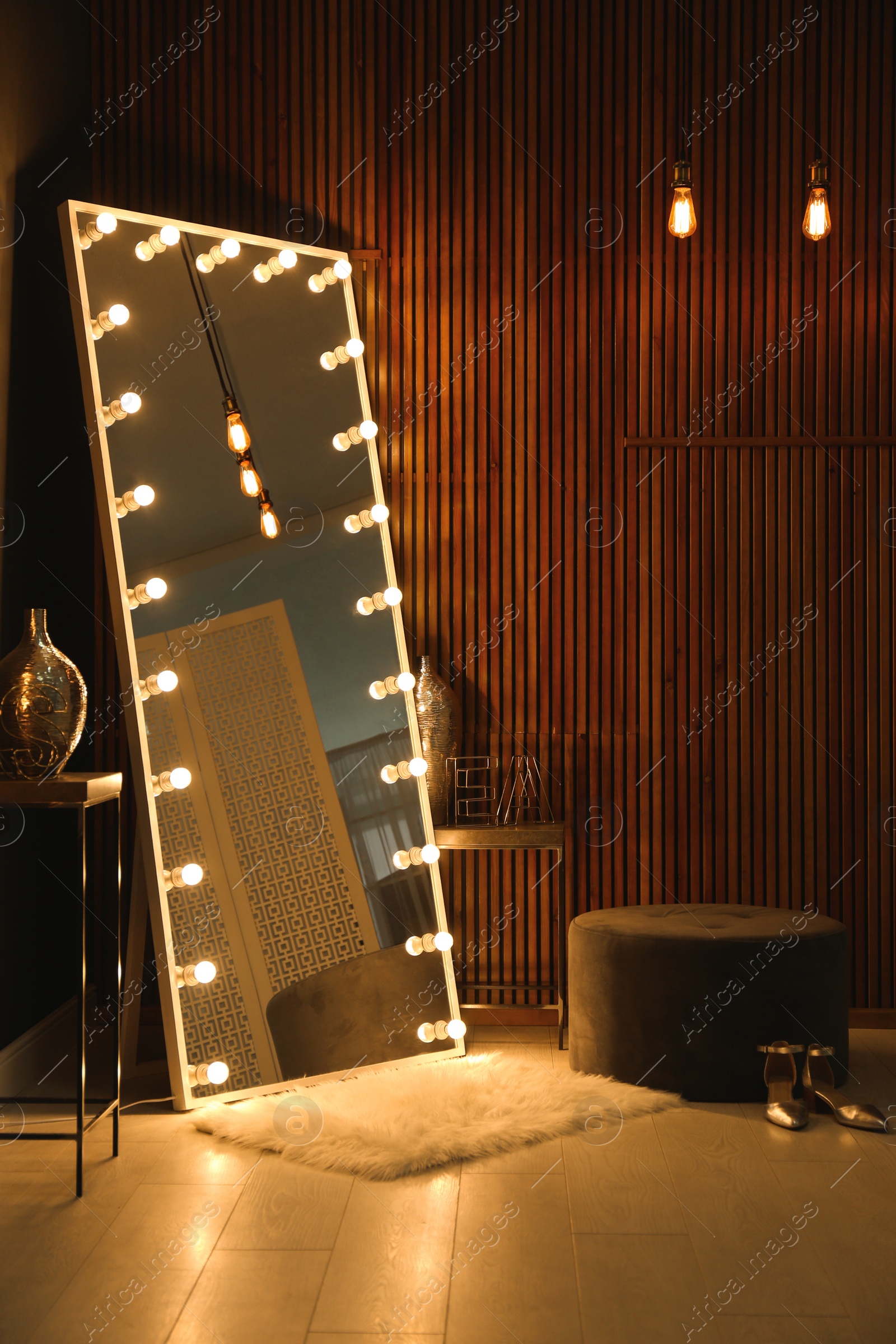 Photo of Stylish large mirror with light bulbs in dark room. Modern interior design