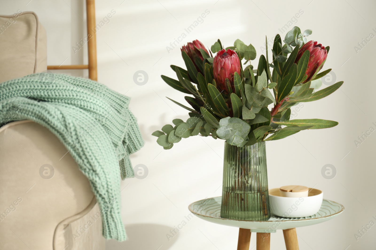 Photo of Vase with bouquet of beautiful Protea flowers on table in room