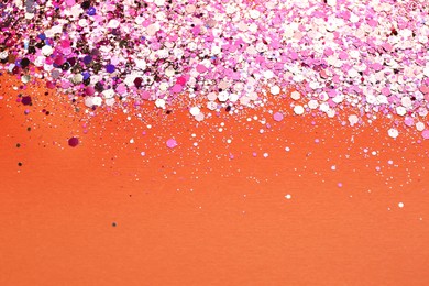 Photo of Shiny bright pink glitter on coral background. Space for text