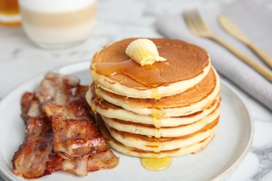 Delicious pancakes with maple syrup, butter and fried bacon on table, closeup
