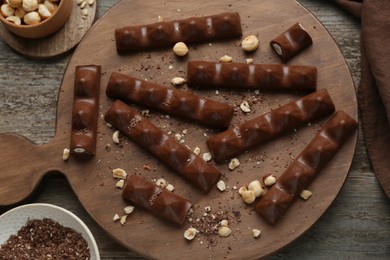 Tasty chocolate bars with nuts on wooden table, flat lay
