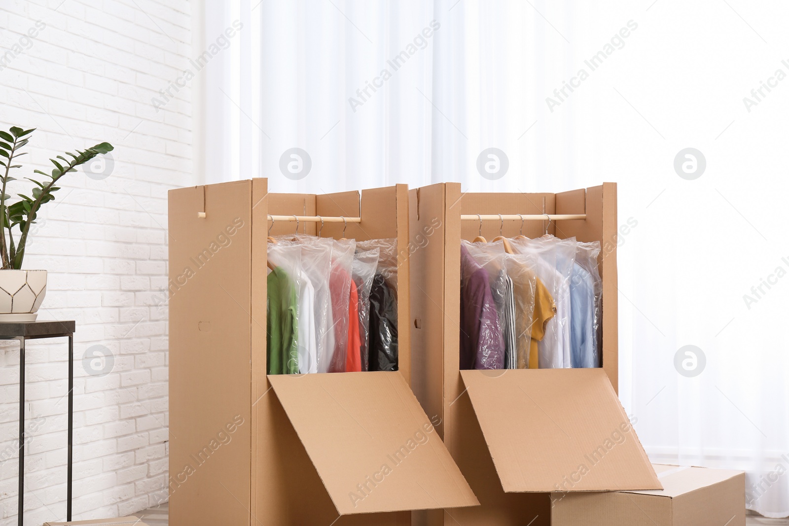 Photo of Wardrobe boxes with clothes near window indoors