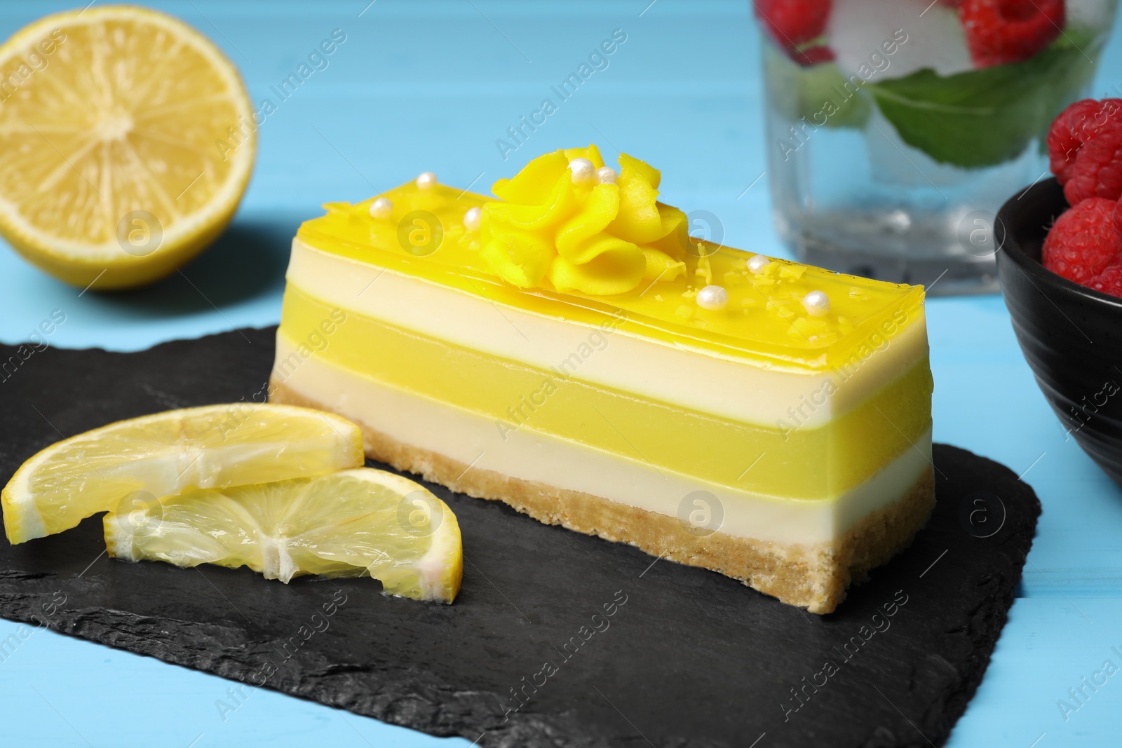 Photo of Delicious cheesecake with lemon on light blue wooden table, closeup