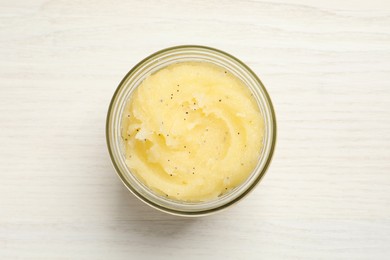 Body scrub in glass jar on white wooden table, top view