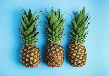 Photo of Fresh ripe juicy pineapples on light blue background, flat lay