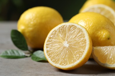 Photo of Fresh lemons and green leaves on grey table outdoors, closeup