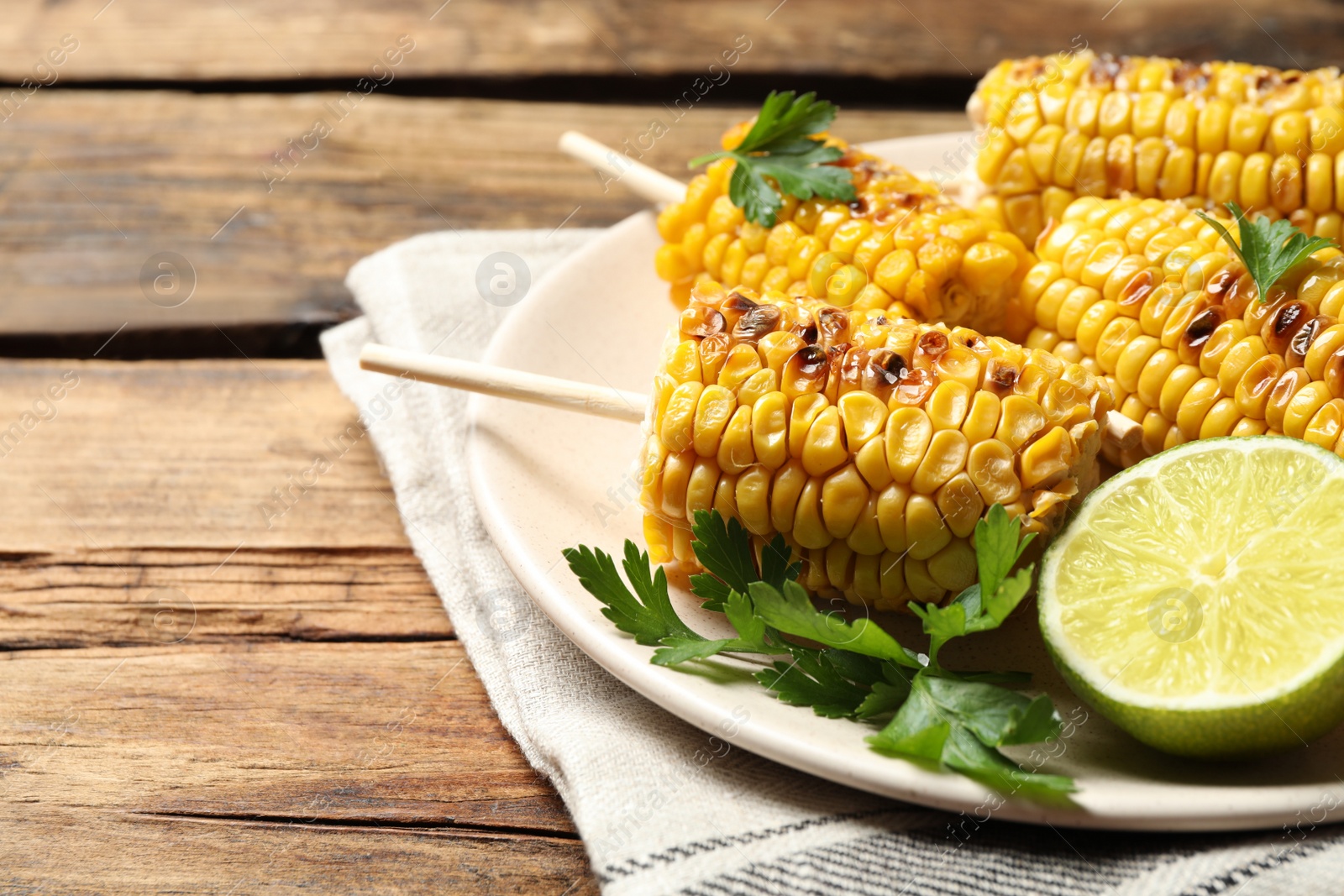 Photo of Tasty grilled corn on wooden table, space for text
