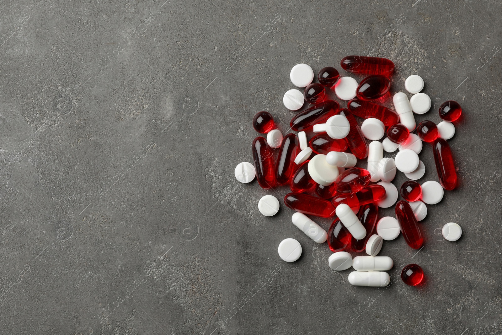 Photo of Heap of different pills on grey background, top view. Space for text