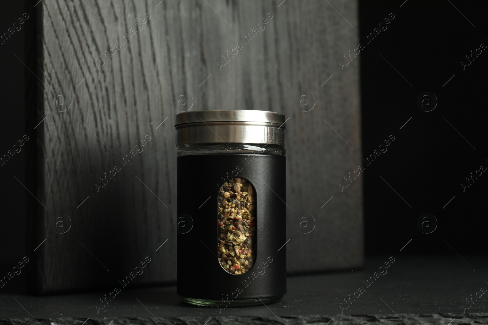 Photo of One stylish pepper shaker on black table