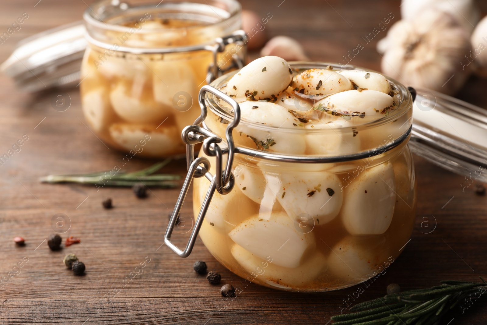 Photo of Preserved garlic in glass jar on wooden table, closeup