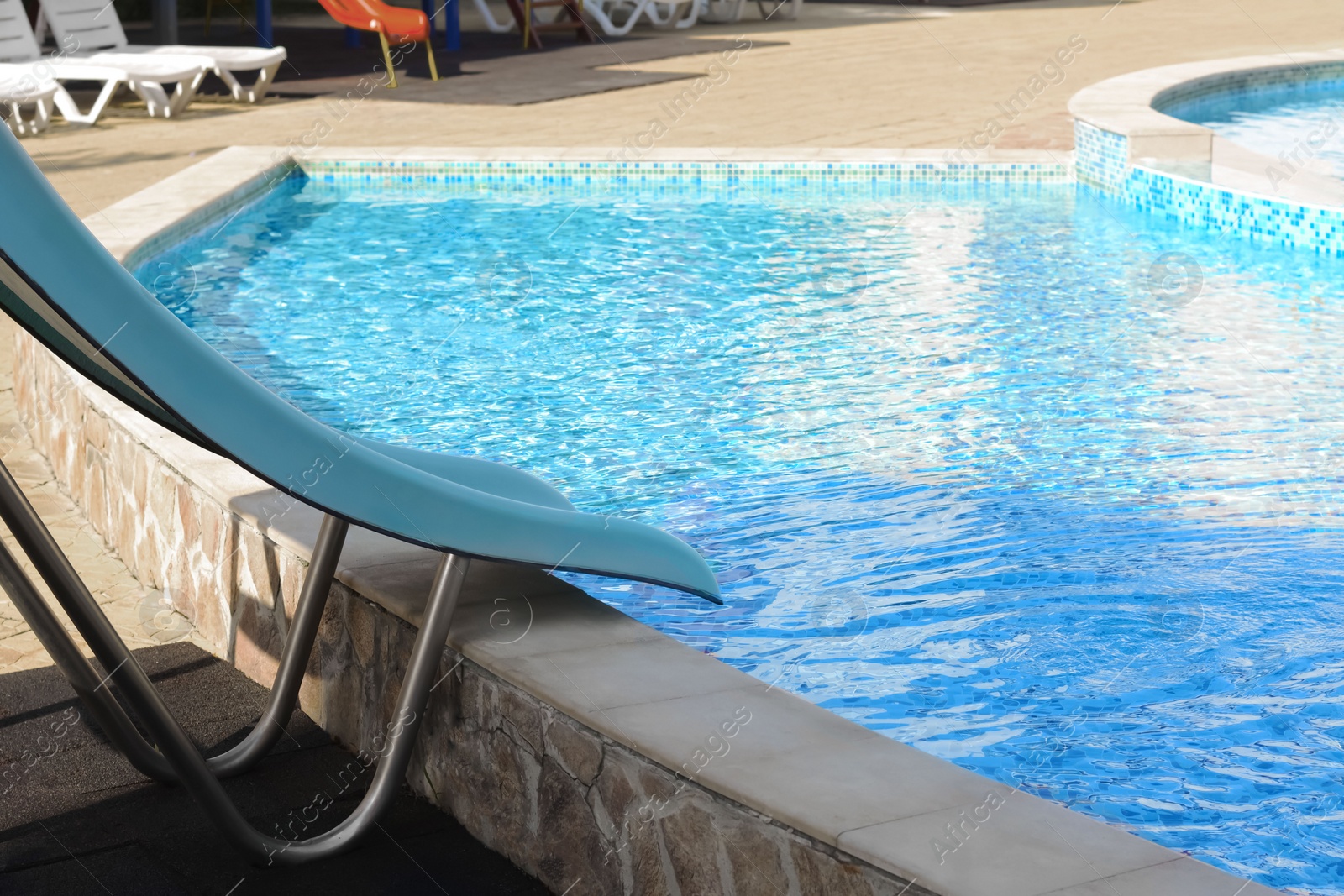 Photo of Outdoor swimming pool with waterslide on sunny day