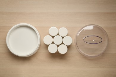 Modern yogurt maker and jars on wooden table, flat lay