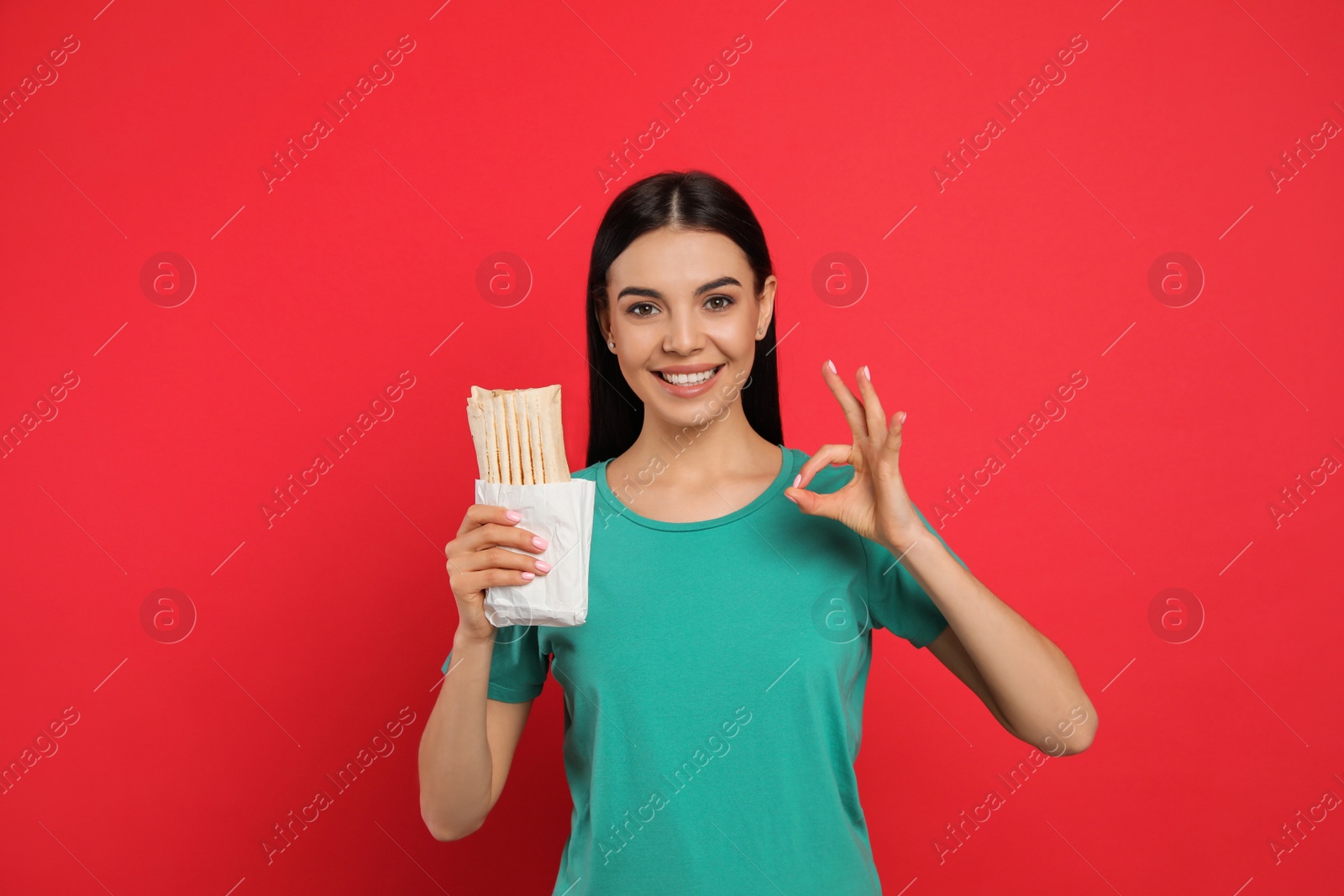 Photo of Happy young woman with delicious shawarma on red background